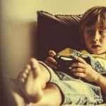 Little boy stares off into space as he plays video games.