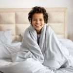A child smiles while wrapped in a weighted blanket